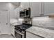 Focus on stainless gas range and microwave in updated kitchen with granite countertops and modern backsplash at 1883 Frisco Way, Suwanee, GA 30024