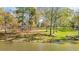 Beautiful waterfront property with a gentle slope, mature trees, and a glimpse of the house nestled among the trees at 205 Pine Knott Rd, Fayetteville, GA 30214