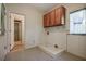 Well-lit laundry room featuring wood cabinets, utility sink, and neutral flooring at 205 Pine Knott Rd, Fayetteville, GA 30214