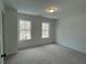 This bedroom has neutral carpeting, a modern ceiling light and two large windows for natural lighting at 1932 Appian Aly, Kennesaw, GA 30144