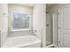 Bathroom featuring a soaking tub, glass-enclosed shower, neutral finishes and natural light at 5063 Lower Elm St, Atlanta, GA 30349