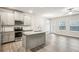 An open concept kitchen and living room space with stainless steel appliances and grey cabinetry at 5063 Lower Elm St, Atlanta, GA 30349