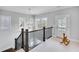 Bright hallway with dark wood staircase, charming decor, and natural light from the windows at 2304 Isla Run, Woodstock, GA 30188
