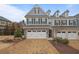 Charming townhome with a brick and gray facade, complemented by a two-car garage and patterned brick driveway at 100 Duval Dr, Alpharetta, GA 30009