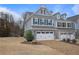 Stylish townhome featuring a two-car garage and brick driveway, set against a backdrop of trees and blue sky at 100 Duval Dr, Alpharetta, GA 30009