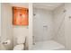 Bright bathroom featuring a white tub with tile surround and an orange cabinet above the toilet at 2658 Stonehenge Ct, Dunwoody, GA 30360