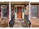 Inviting front porch with brick columns, dark wood door, decorative shutters, and well maintained landscaping at 2658 Stonehenge Ct, Dunwoody, GA 30360