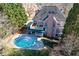 Aerial view of backyard featuring pool, patio, deck, and multi-story home with brick chimney at 2560 Millwater Xing, Dacula, GA 30019
