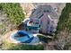 Aerial view of a home's backyard featuring a covered pool, multi-tiered deck, brick patio and lush landscaping at 2560 Millwater Xing, Dacula, GA 30019