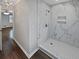 Bathroom showcasing a walk-in shower with marble tiling, a shower niche, and dark wood vinyl flooring at 6390 E Stubbs Rd, Atlanta, GA 30349