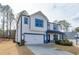 Exterior shot showcasing two story home with blue trim, a two-car garage, and a modern design at 3410 Summerpoint Xing, Cumming, GA 30028