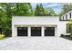 Striking three-car garage featuring black doors, a white brick facade, and a light gray paver driveway at 42 Blackland Nw Rd, Atlanta, GA 30342