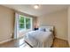 Bright bedroom featuring a large window offering natural light, a comfortable bed and wood flooring at 6690 Bridge Brook Ovlk, Cumming, GA 30028