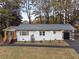 Charming one-story home with a fresh white exterior, a gray roof, a modern garage door and a lovely manicured lawn at 1970 Capri Dr, Decatur, GA 30032