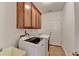 Laundry room with washer, dryer, utility sink, wooden cabinets, and tile flooring at 337 Inverness Ave, Mcdonough, GA 30253