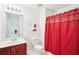 Bright bathroom with a cherry vanity, large mirror, and decorative red shower curtain at 248 Allegrini Dr, Atlanta, GA 30349