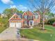 Beautiful two-story brick home with a lush green lawn and a two-car garage on a sunny day at 608 Chickory Ct, Woodstock, GA 30188