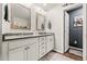 Bathroom with dual sinks, framed mirrors, white cabinets, gray countertop, and modern lighting at 613 Everett Ln, Woodstock, GA 30188