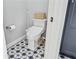 Close up of a toilet room featuring a toilet, white walls, star tile floor and gray door at 9135 Etching Overlook, Johns Creek, GA 30097