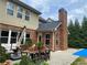 Outdoor patio with a dining set, lounge seating, and a view of the brick chimney and mature trees at 3553 Old Maple Dr, Johns Creek, GA 30022