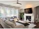 Cozy living room featuring fireplace, TV, plush sofa, and natural light at 3553 Old Maple Dr, Johns Creek, GA 30022