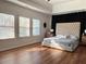 Bright bedroom featuring large windows, hardwood floors, and a tufted headboard at 3553 Old Maple Dr, Johns Creek, GA 30022