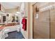 Bright bathroom featuring a glass shower, tiled floors, and a spacious mirror over a white vanity sink at 6664 Windwood Cir, Douglasville, GA 30135