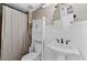 Cozy bathroom with white wainscoting, pedestal sink, toilet, and a shower with a neutral-toned curtain at 343 Woodstone Dr, Marietta, GA 30068