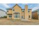 A view of the yellow two-story home with a bay window and a patio in the grassy backyard at 610 Maltese Dr, Atlanta, GA 30349