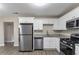 Charming kitchen features stainless steel appliances, white cabinets, granite counters, and wood-look flooring at 645 Plainville Sw Dr, Atlanta, GA 30331