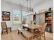 Well-lit dining room with wood table and chairs, complemented by a modern chandelier and large window at 335 Tillman Pass, Woodstock, GA 30188