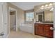 This bathroom boasts a soaking tub with tiled surround, vanity with sink, and a large mirror at 8885 Camp Tree Ct, Winston, GA 30187