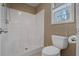 This bathroom features a bright white tiled shower and a white toilet by the window at 8885 Camp Tree Ct, Winston, GA 30187