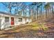 View of a house with a white exterior, a red door, and a spacious backyard surrounded by trees at 147 Reynolds Bridge Rd, Kingston, GA 30145