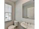 Powder room features a white sink, toilet, mirror and a window offering natural light at 2212 Whistler Ne Way, Lawrenceville, GA 30043