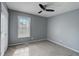 Neutral bedroom featuring gray walls, carpet, and a ceiling fan, illuminated by natural light through a window at 6230 Nellie Se Br, Mableton, GA 30126