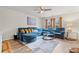 Comfortable living room featuring a plush blue sectional sofa, a ceiling fan, and bright natural light at 310 Indian Lake Trl, Villa Rica, GA 30180