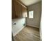 Bright laundry room features wood-look flooring, ample cabinet storage, and a window for natural light at 1270 Sandhill Hulett Rd, Villa Rica, GA 30180