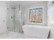 Modern bathroom featuring a glass-enclosed shower and a freestanding tub overlooking an outdoor view at 4051 Ridgehurst Se Dr, Smyrna, GA 30080