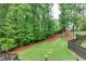 Lush backyard featuring mature trees, landscaping, and partial fence with wooded view at 6225 Leeward Tide Ct, Cumming, GA 30041