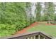 View of the backyard with a border of mulch, grass, mature trees, and a retaining wall at 6225 Leeward Tide Ct, Cumming, GA 30041