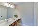A bathroom featuring a white countertop with vanity and a framed mirror with lighting at 6225 Leeward Tide Ct, Cumming, GA 30041