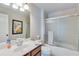Bright bathroom featuring a white vanity, framed mirror and a bathtub with sliding glass doors at 6225 Leeward Tide Ct, Cumming, GA 30041