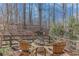 Outdoor fire pit area with chairs surrounded by lush greenery and mature trees in backyard at 6225 Leeward Tide Ct, Cumming, GA 30041