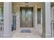 Inviting front porch with brick columns, detailed iron front door, and brick floor at 6225 Leeward Tide Ct, Cumming, GA 30041