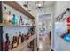 Hallway featuring custom shelving stocked with an array of liquor bottles, connecting to the dining and kitchen areas at 6225 Leeward Tide Ct, Cumming, GA 30041
