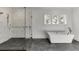Bathroom featuring glass shower, soaking tub, three windows, and marble floors at 2427 Wolf Meadow Ln, Buford, GA 30518