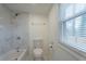 Well-lit bathroom featuring a bathtub with a shower, marble tiling, and a modern toilet for comfort at 500 Pomona Sw Cir, Atlanta, GA 30315