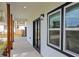 View of covered side porch showing concrete floor, wood columns and framed windows and black trimmed exterior door at 221 Cobb St, Palmetto, GA 30268