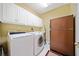 Well-lit laundry room with washer, dryer, white cabinets, and a retro brown refrigerator at 210 Lawn Market, Sharpsburg, GA 30277